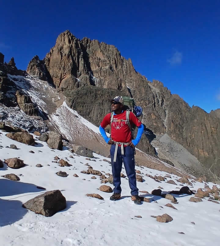 Best Month to Hike Mount Kenya - Keshi Tours guide posing on the snowy section of Mount Kenya